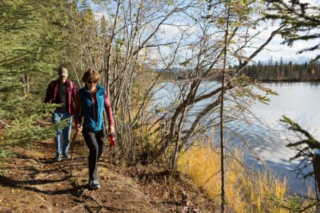 Two people hike next to a lake.